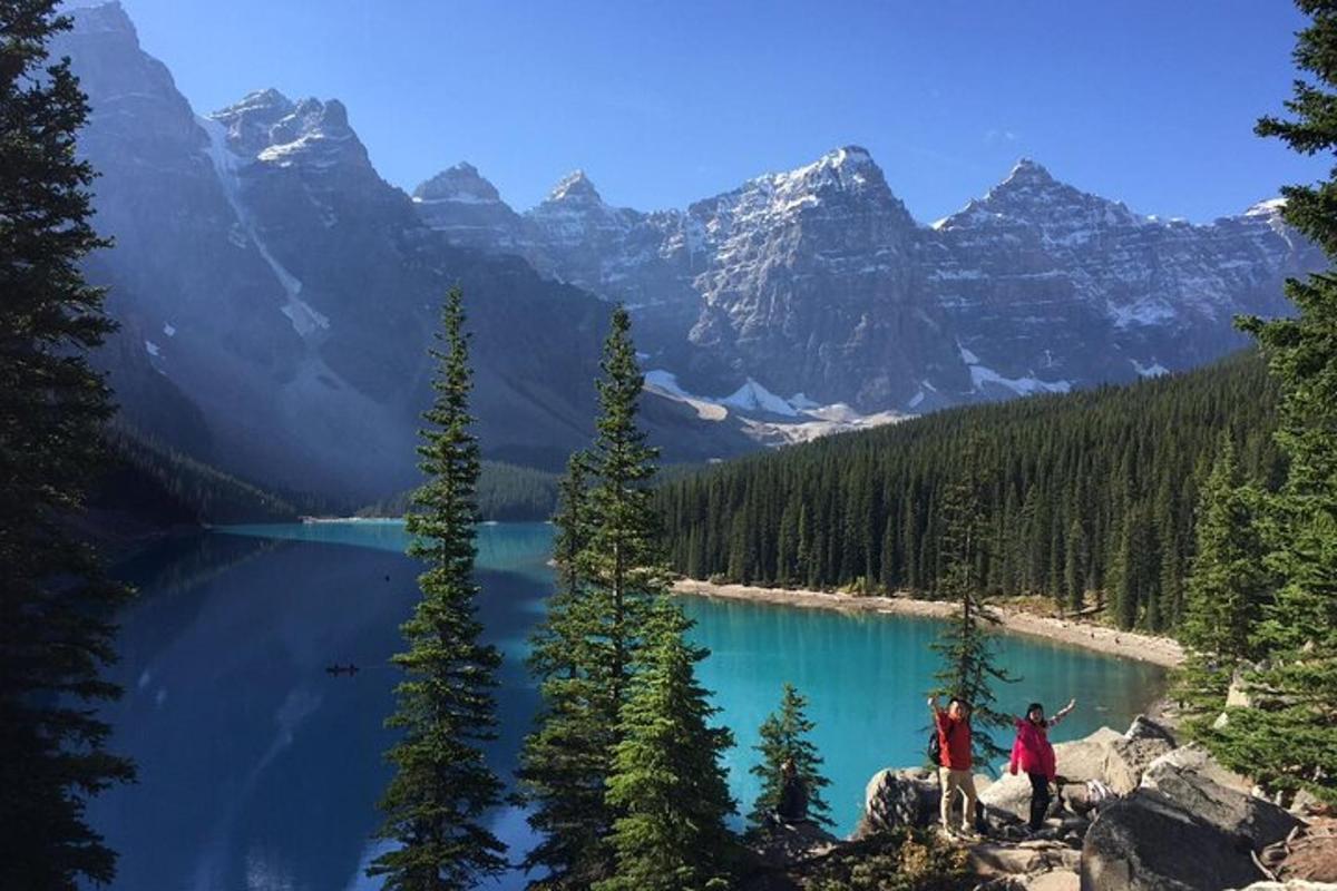 Dos personas de pie sobre una roca cerca de un lago de montaña