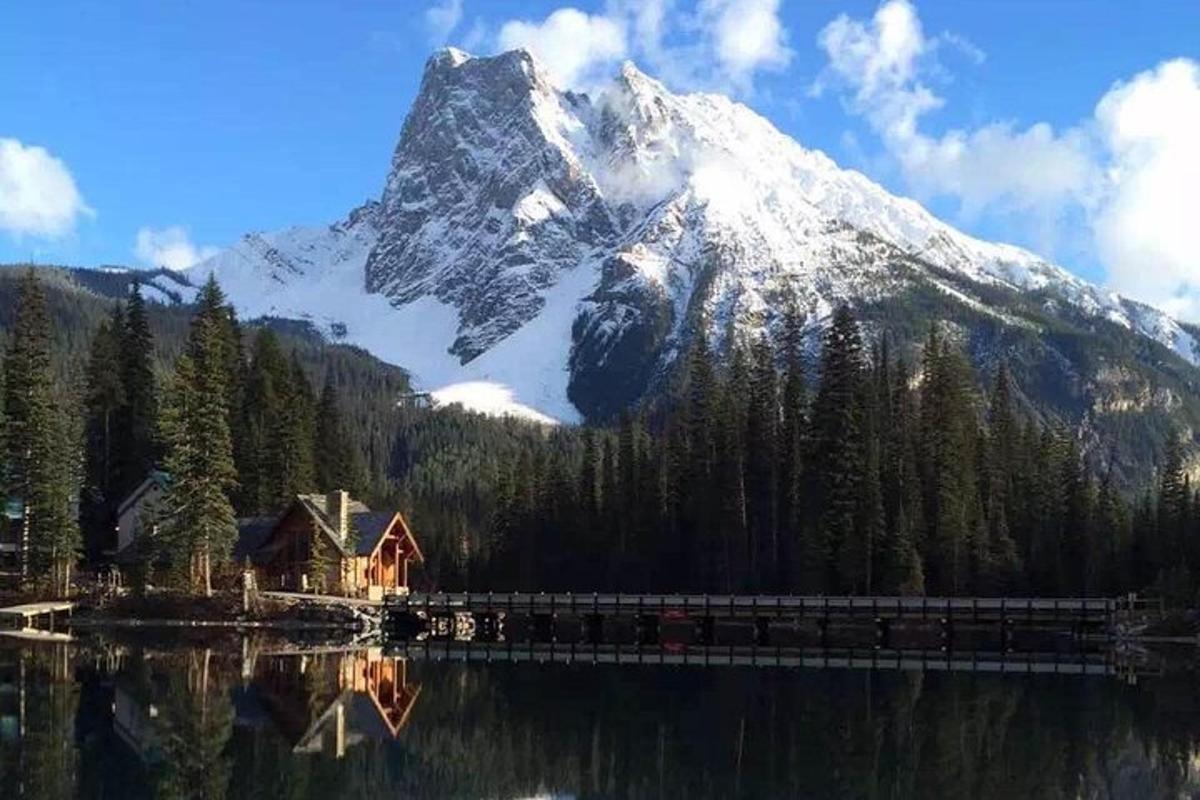 Una montaña cubierta de nieve con una casa y un lago.
