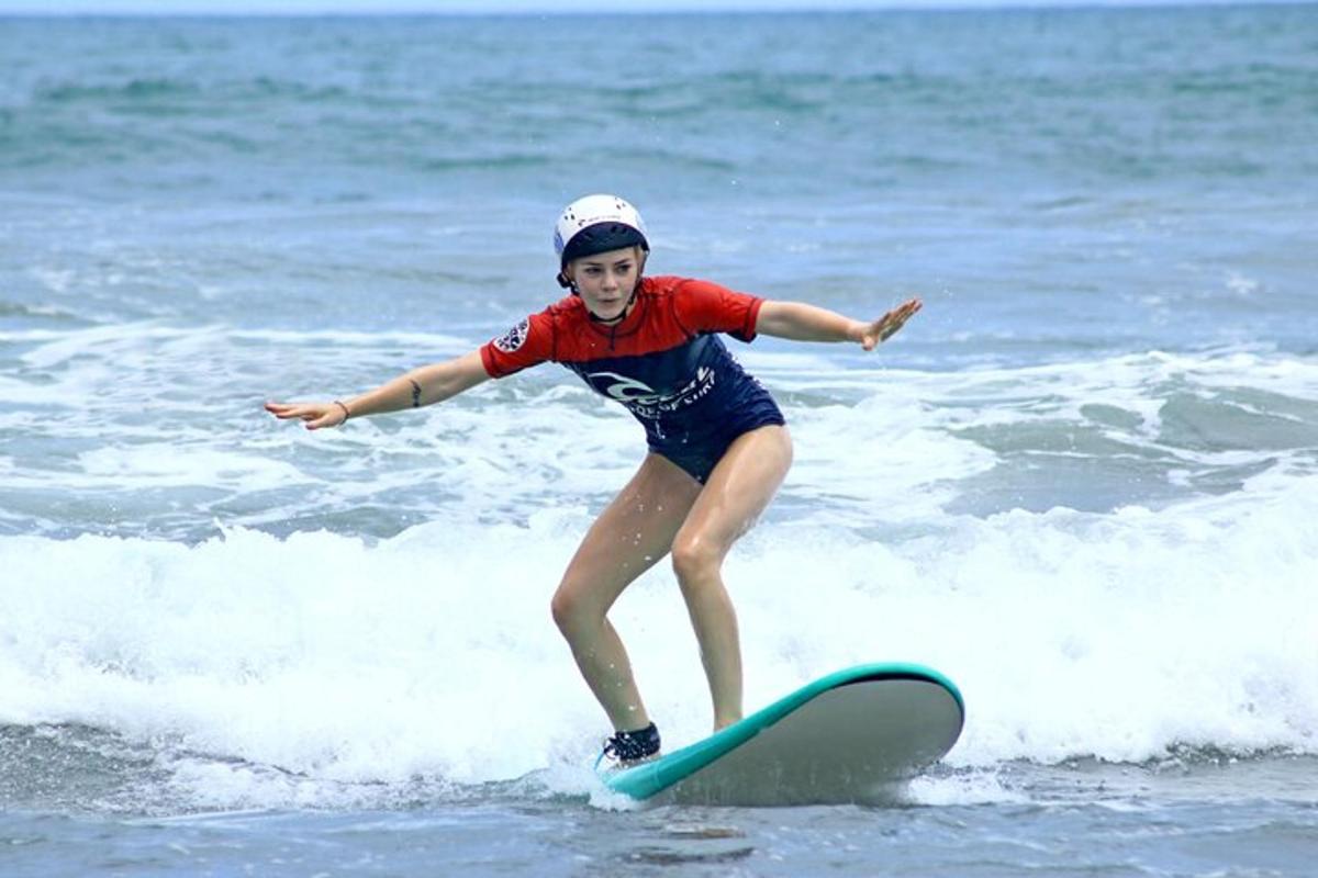 en ung jente som rir på en bølge på et surfebrett i havet