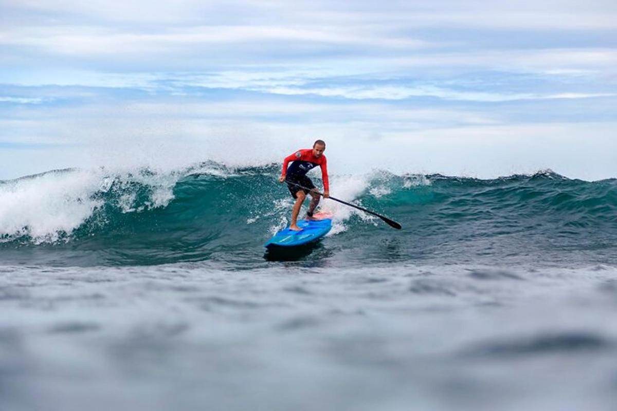 isang lalaking nakasakay sa paddle board sa alon sa karagatan