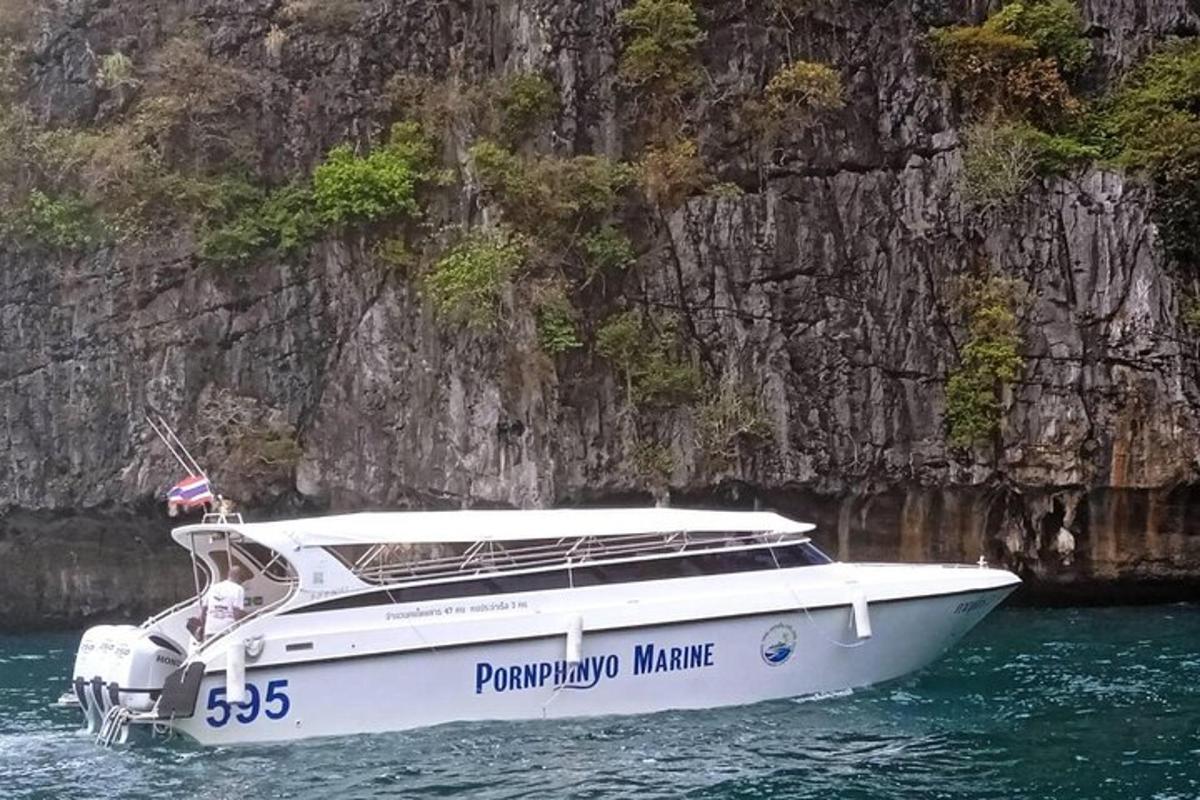 a white boat in the water near a rock wall