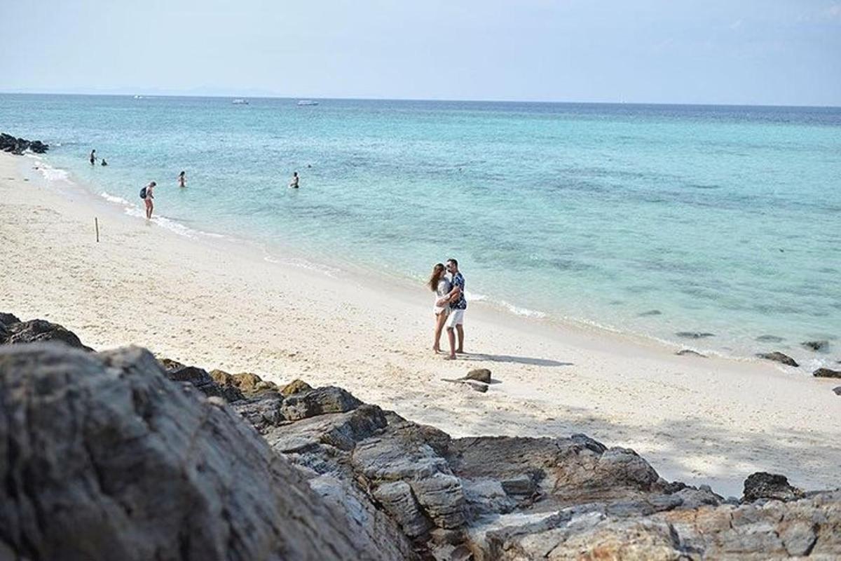 een groep mensen die op een strand loopt