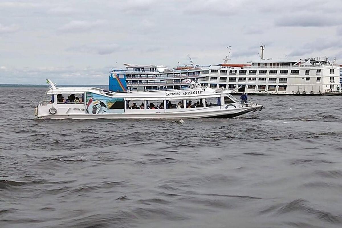 a white boat in the water with a large cruise ship