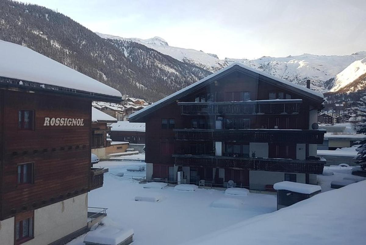 a ski lodge in the snow with mountains in the background