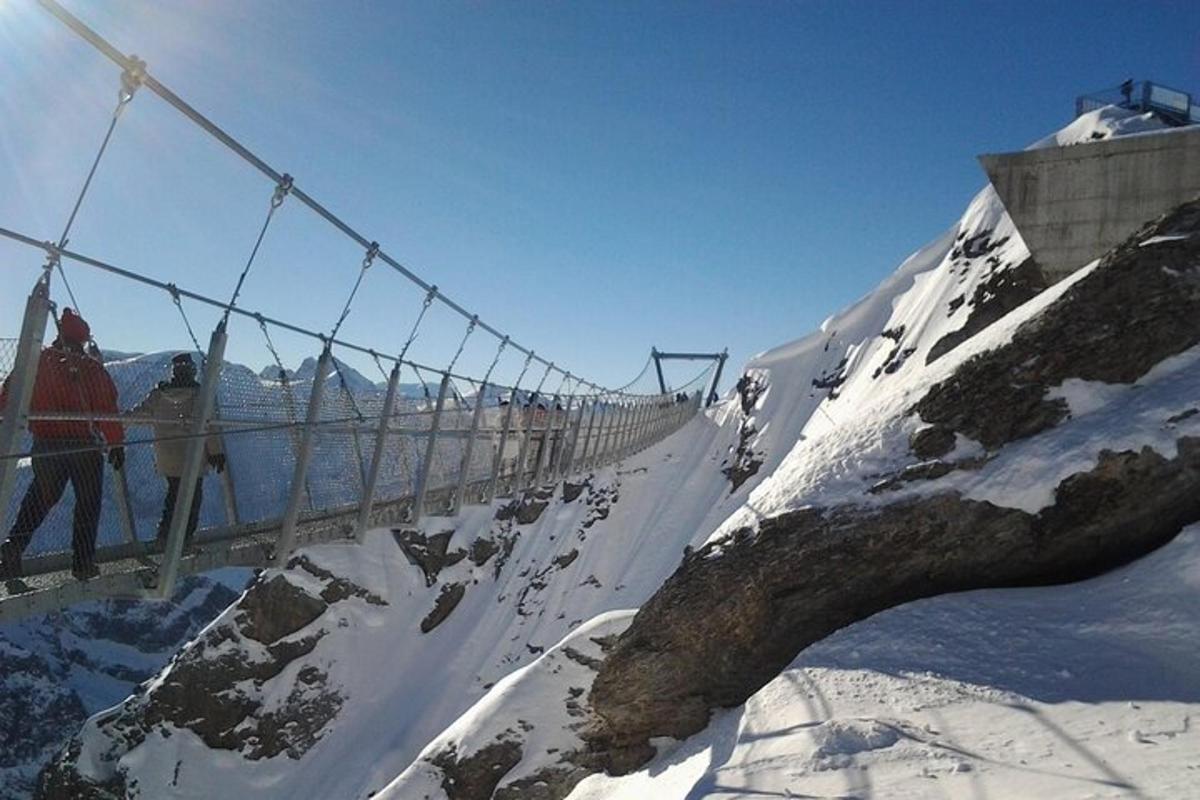 en hengebro på toppen av et snødekt fjell