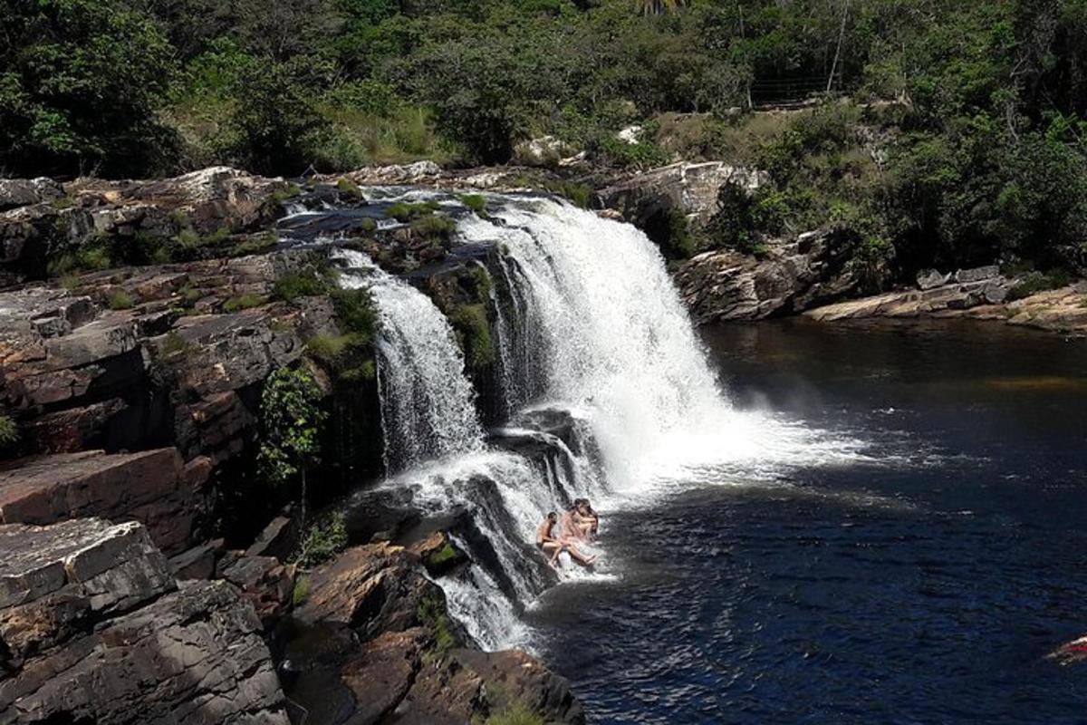 a person in the water in front of a waterfall