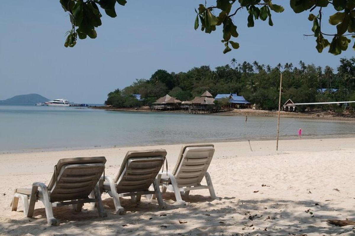 three chairs sitting on a beach next to the water