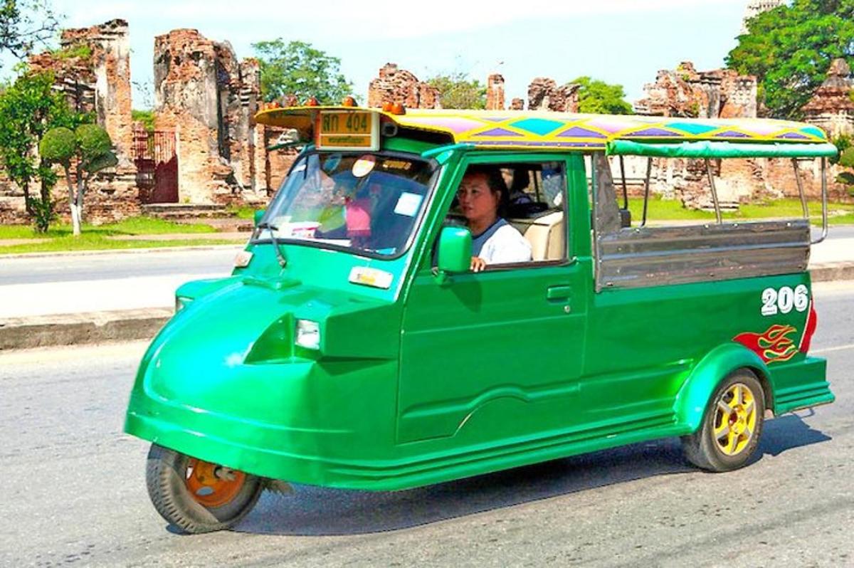 una persona conduciendo un pequeño coche verde con un paraguas