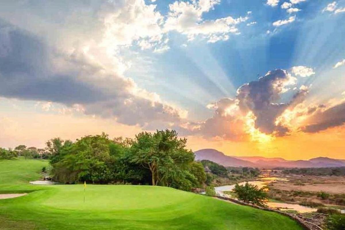 lapangan golf hijau dengan latar belakang matahari terbenam