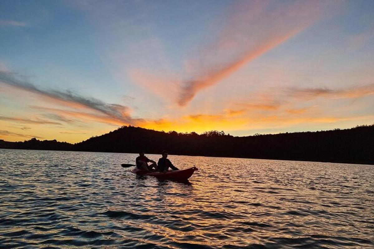 three people in a canoe on a lake at sunset