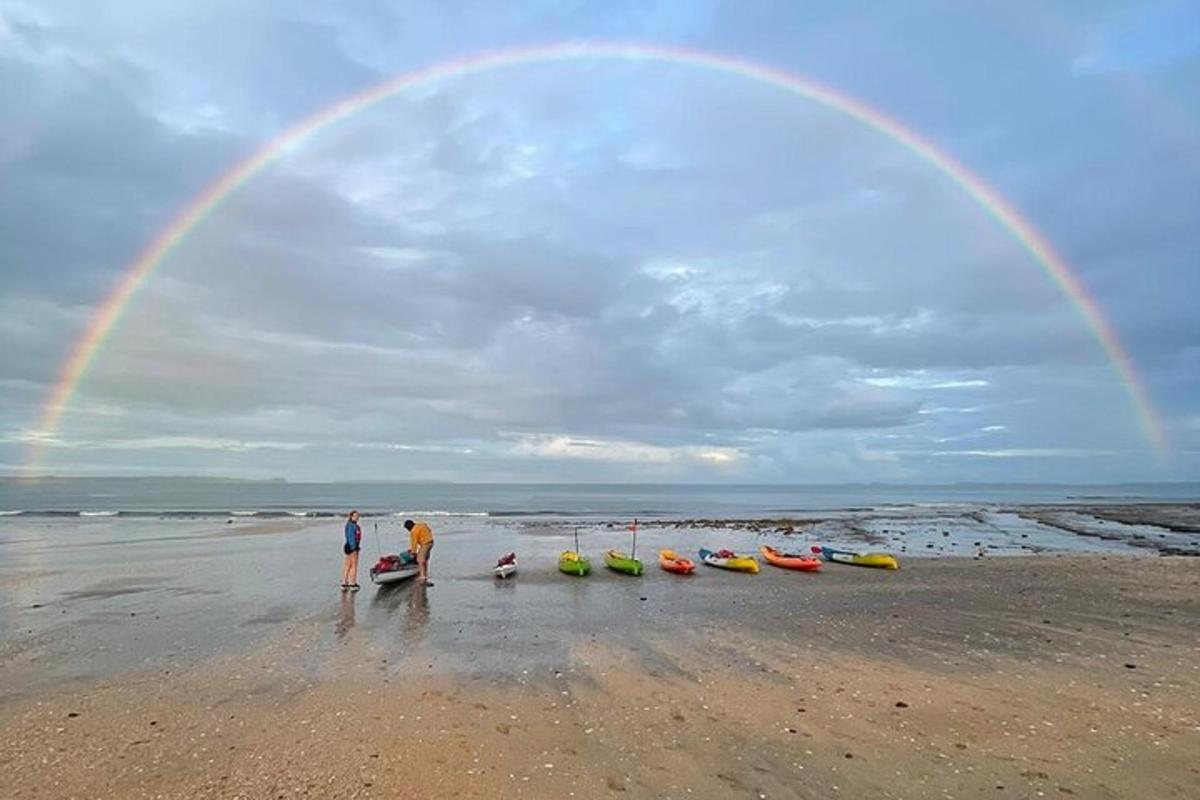 two people standing on a beach with a rainbow