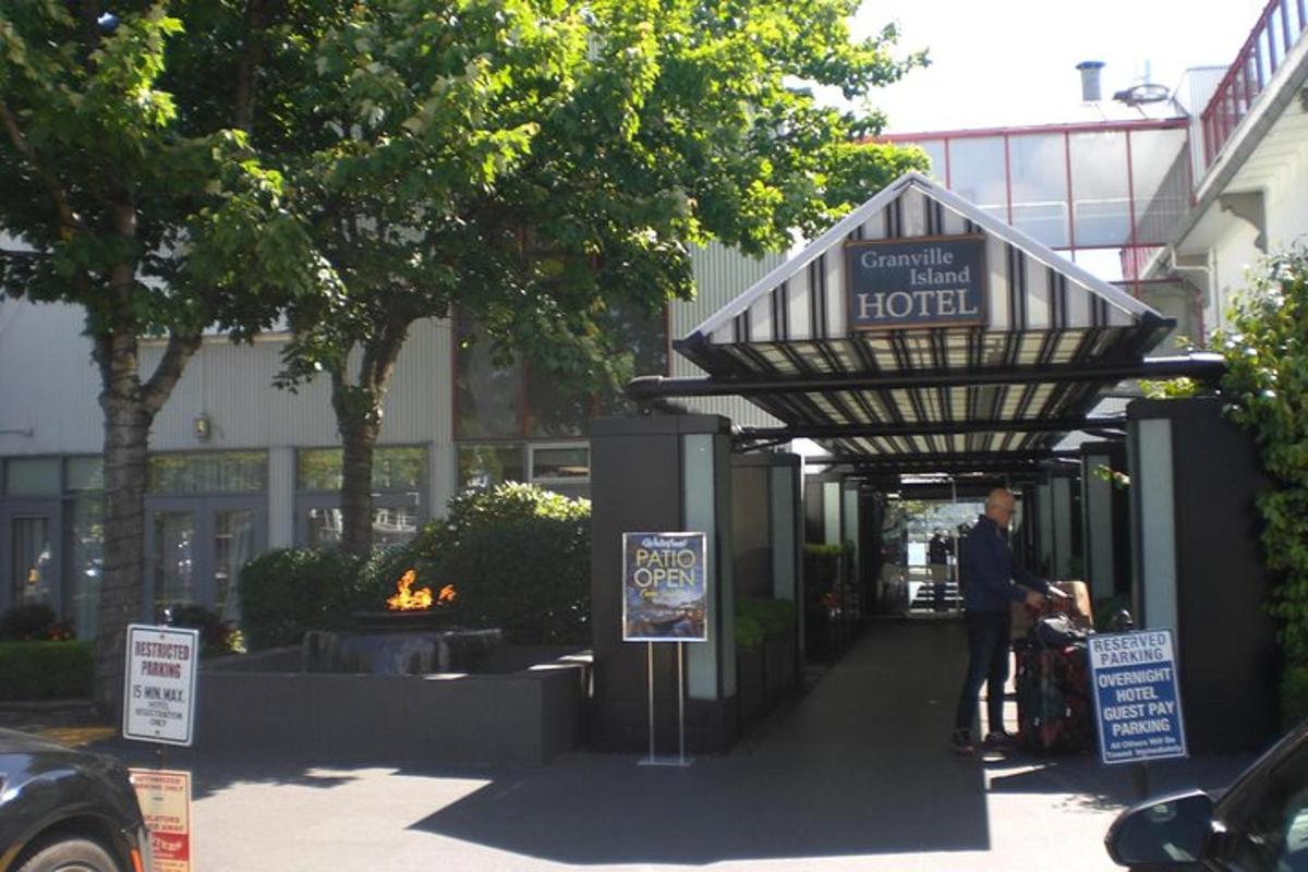 Un hombre parado debajo de un cartel de hotel en una acera.