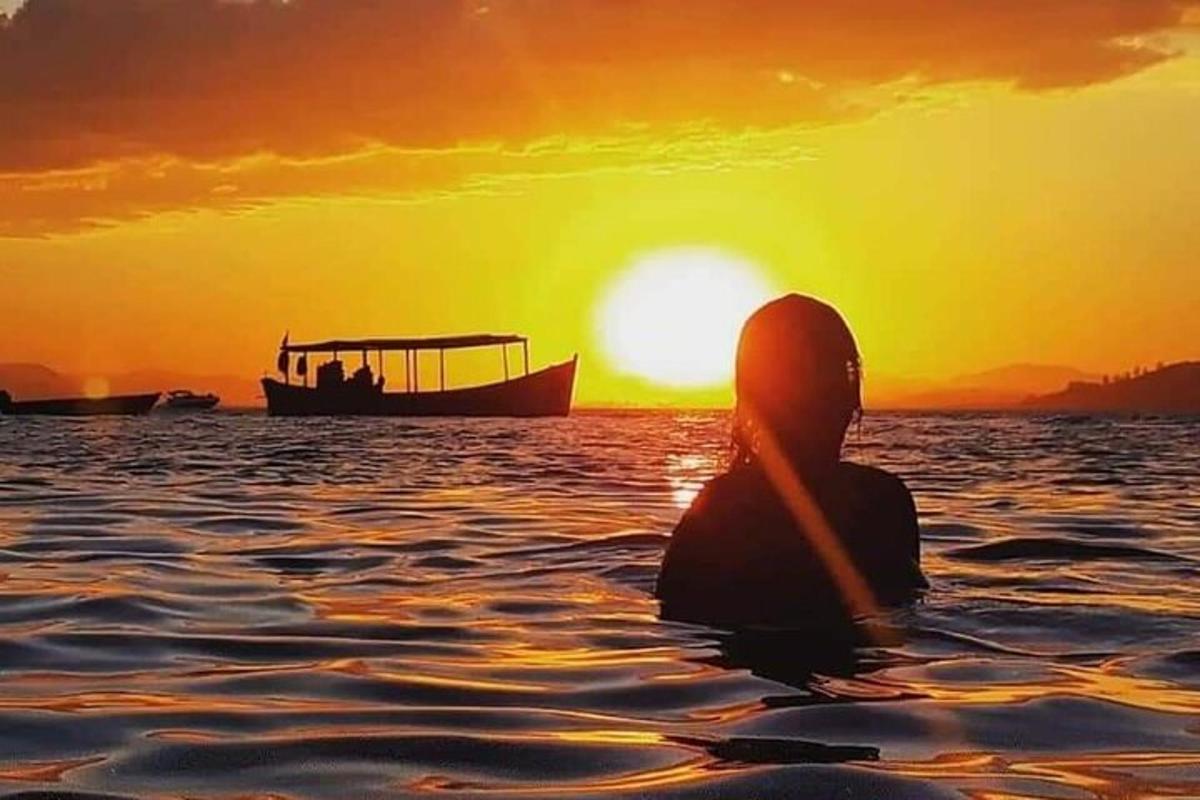 eine Person, die im Wasser sitzt und den Sonnenuntergang beobachtet