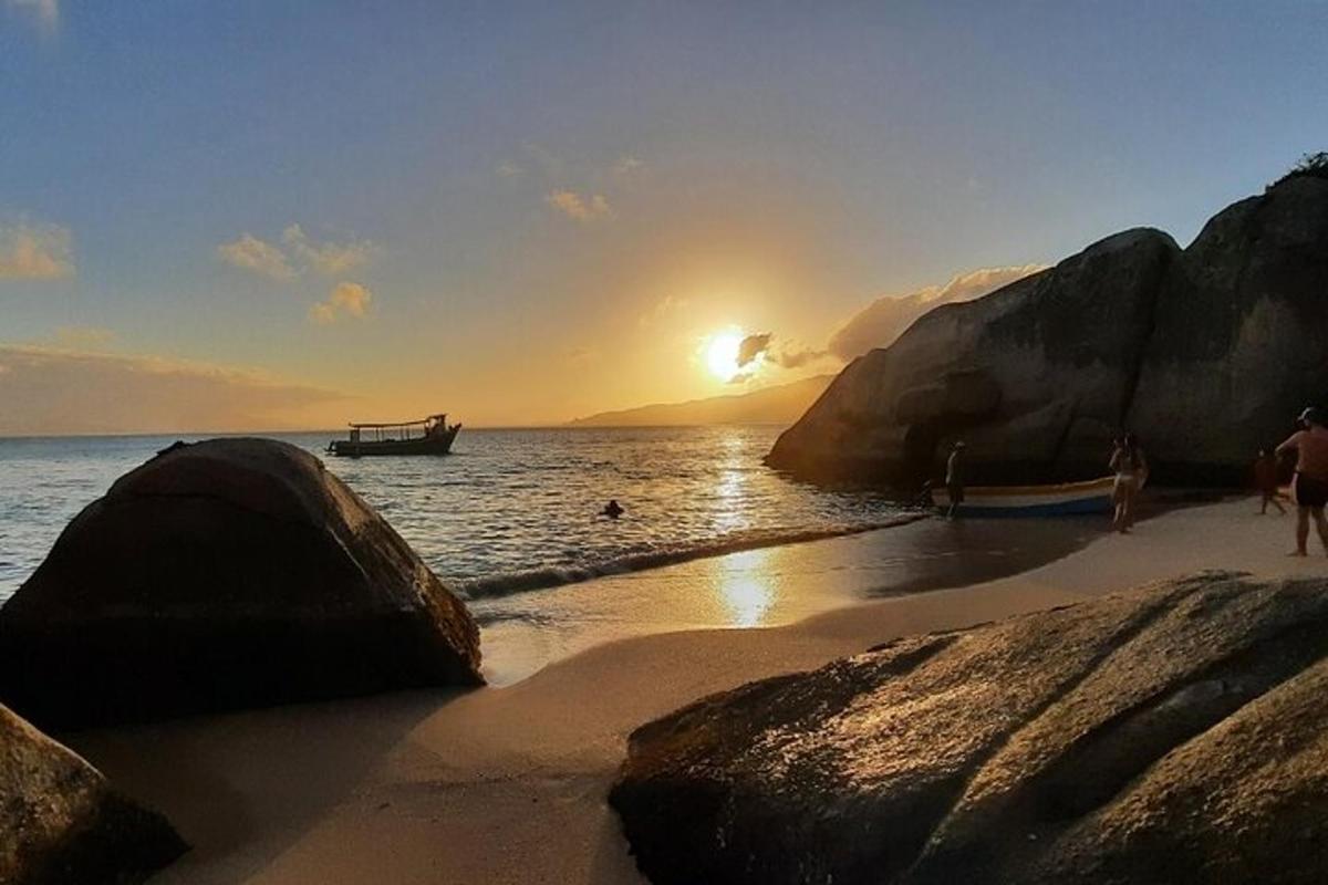 ein Sonnenuntergang an einem Strand mit einem Boot im Wasser