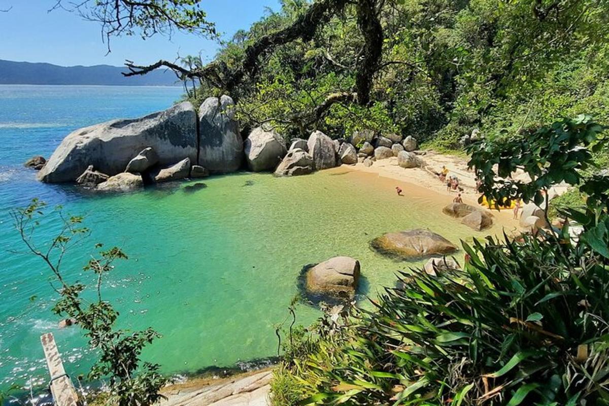 ein Strand mit Felsen und Menschen im Wasser