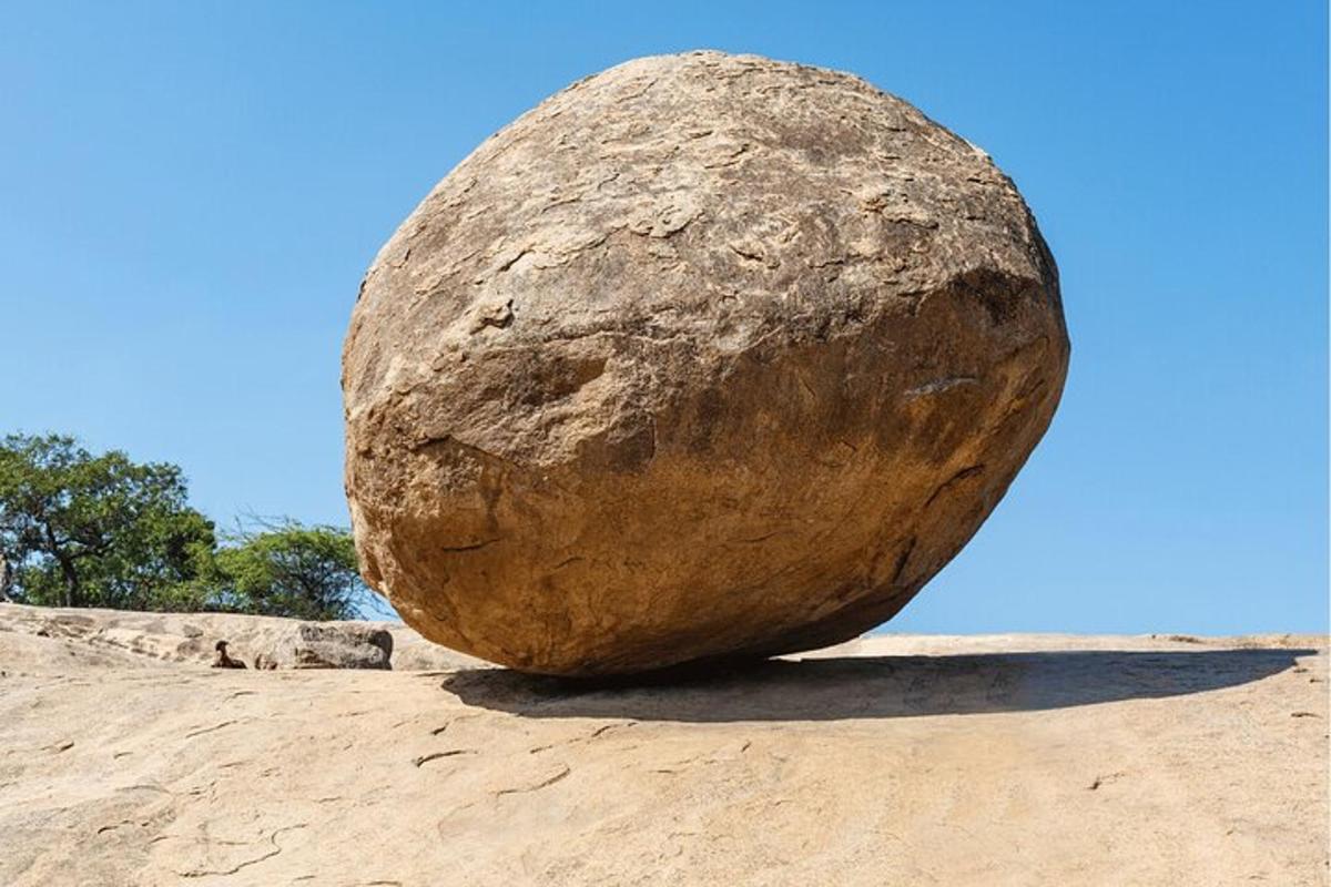 a large rock sitting on top of a dirt field