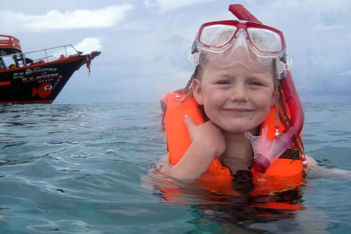 a young girl in the water with a boat in the background