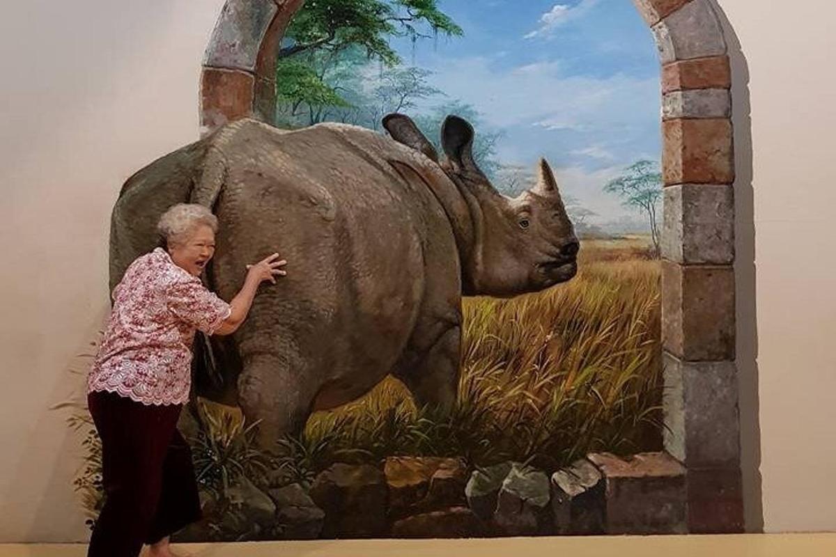 a woman standing next to a statue of a rhino