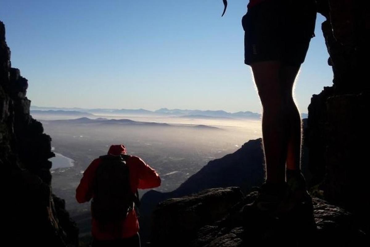 una persona in piedi sulla cima di una montagna che guarda il panorama