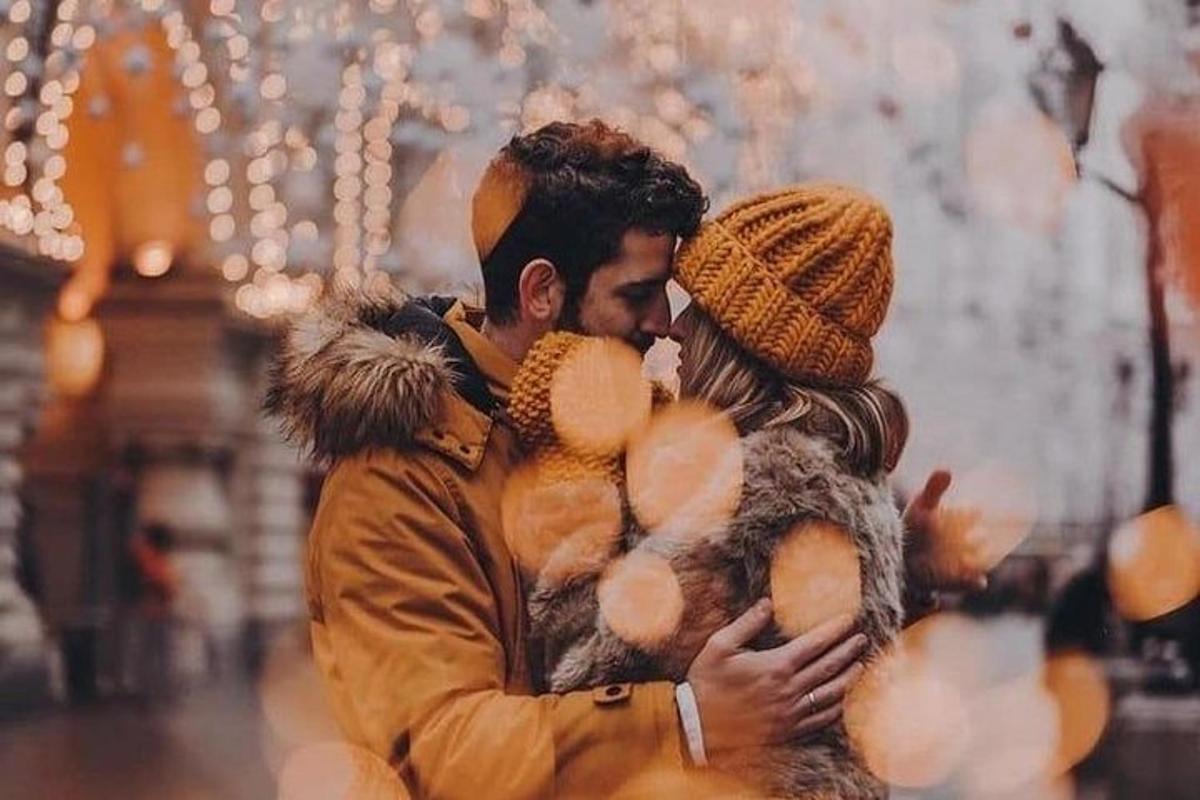 a man and a woman are hugging in front of christmas lights