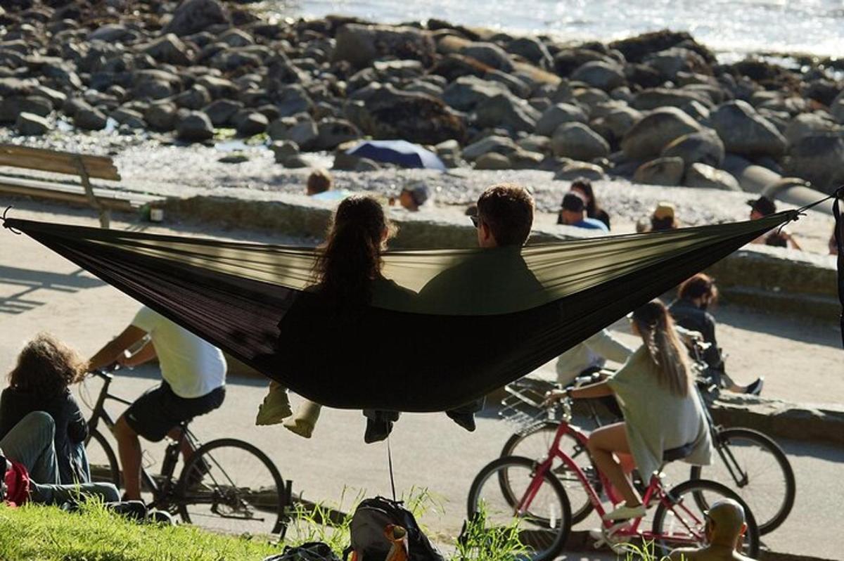a couple sitting in a hammock on their bikes at the beach