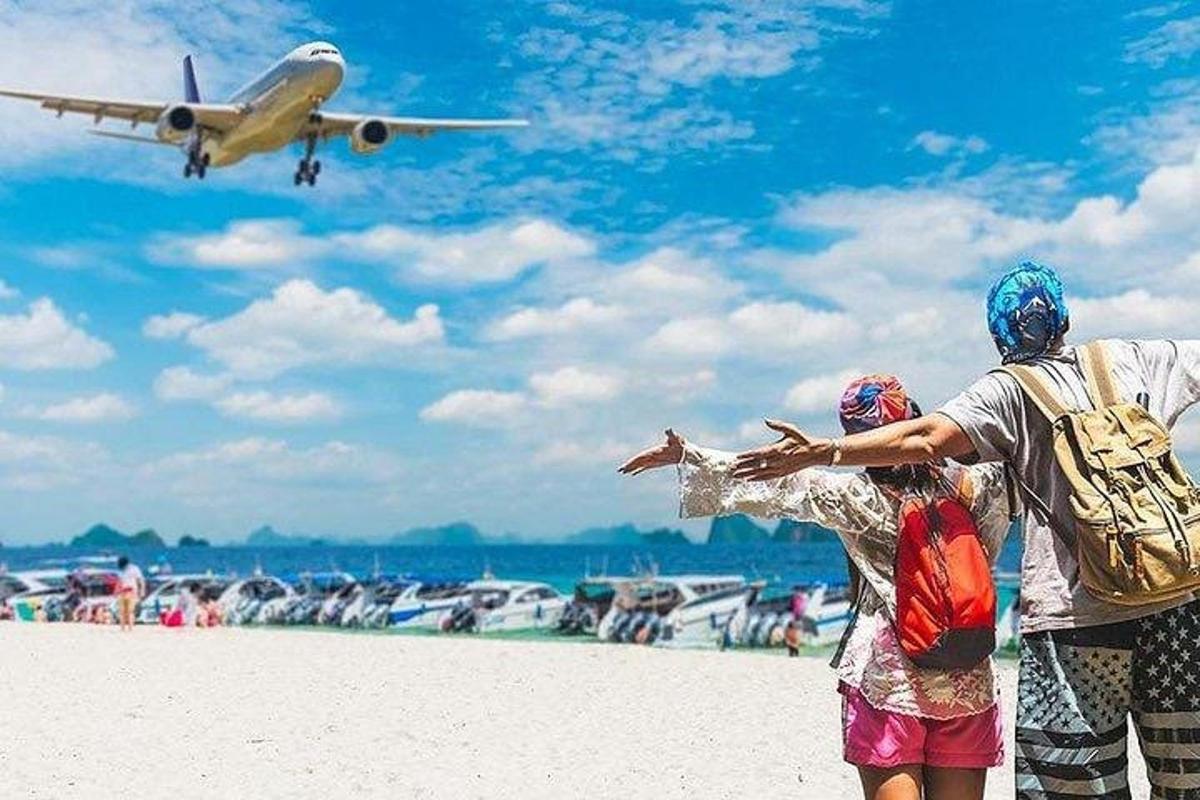 dua orang berdiri di pantai melihat kapal terbang