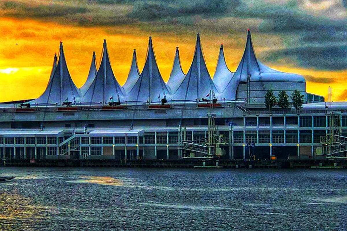 un edificio sull'acqua con un tramonto sullo sfondo