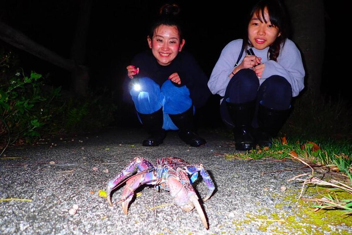 two people sitting next to a crab on the ground