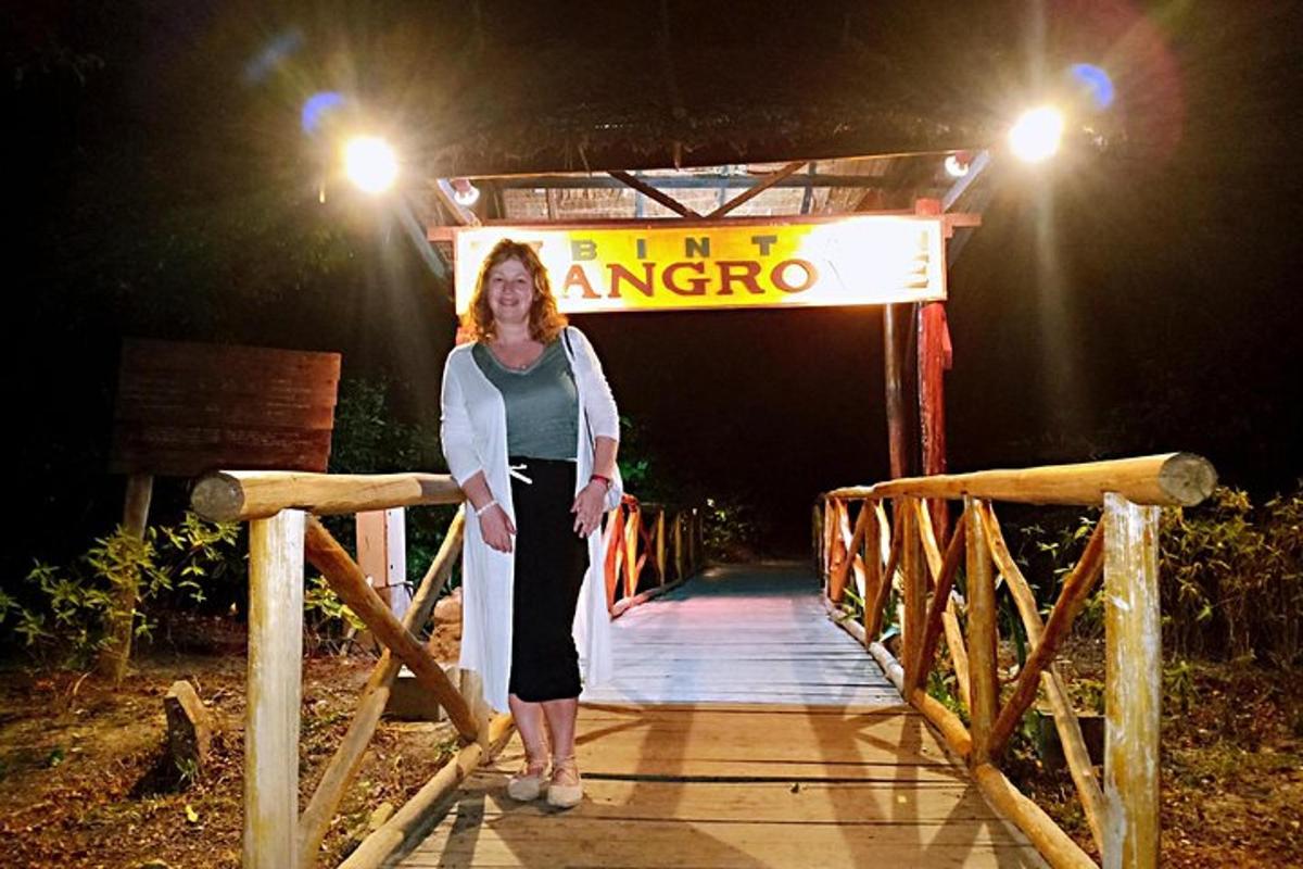a woman standing on a wooden bridge at night