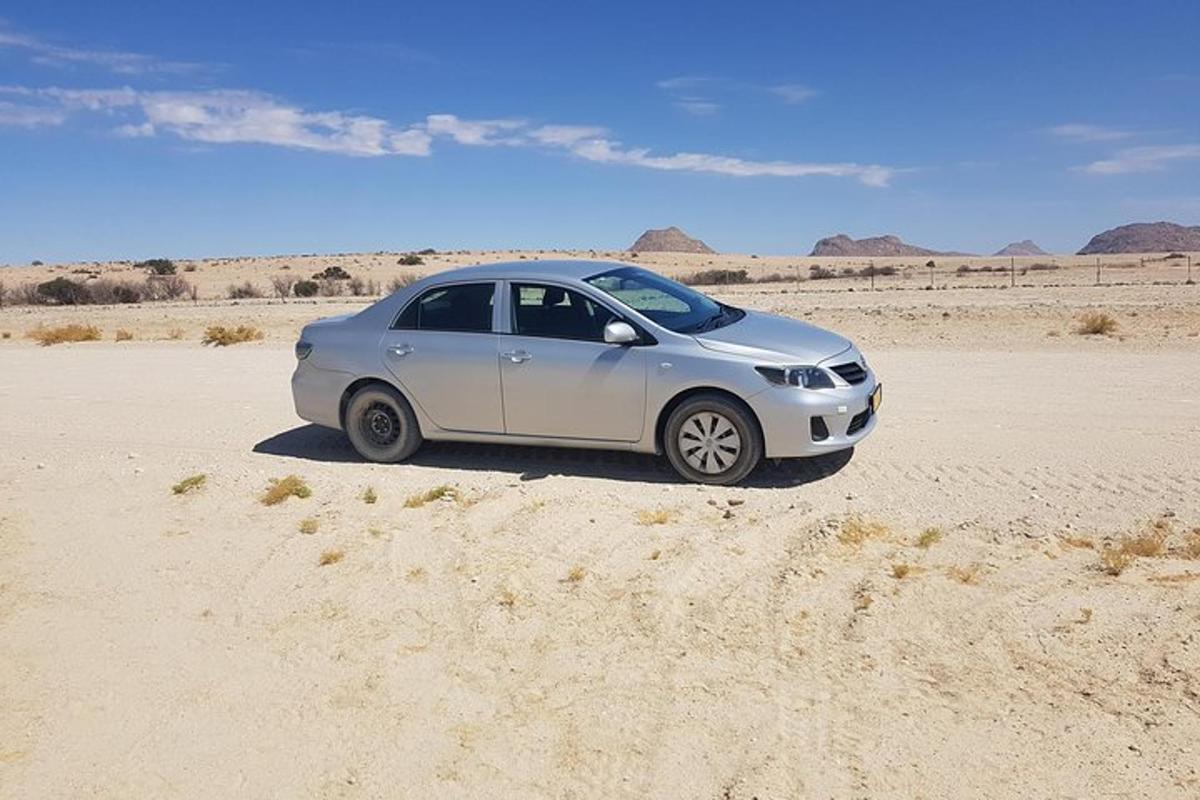 a silver car parked in the middle of the desert