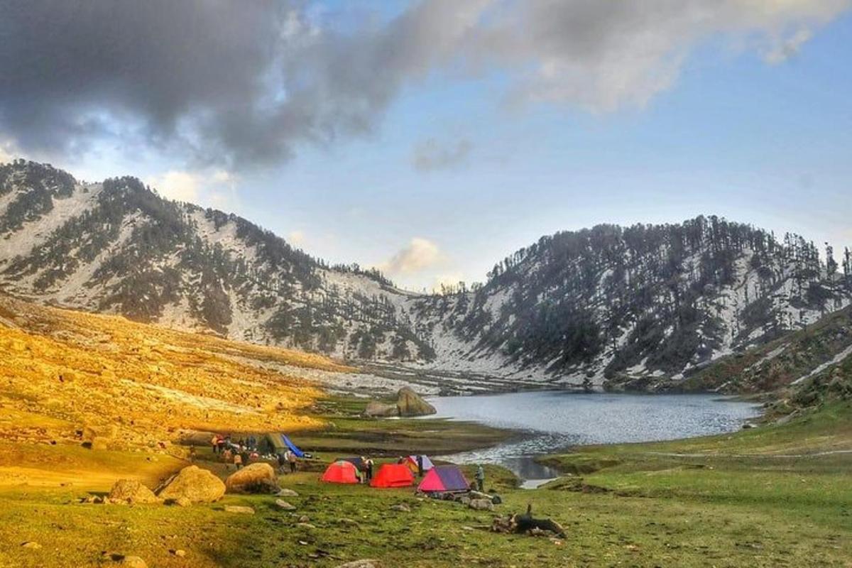 a group of tents in a field next to a lake