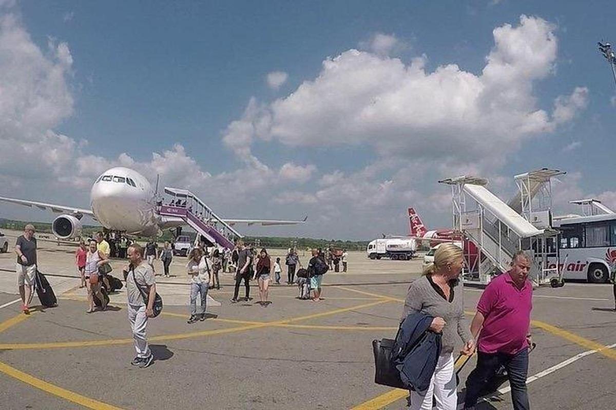 skupina ljudi, ki se vkrcavajo na letalo na vzletno-pristajalni stezi