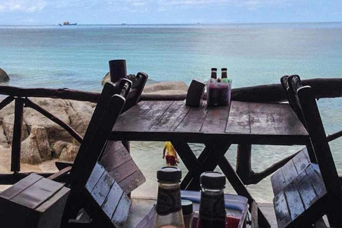 un tavolo da picnic sulla spiaggia con sopra delle bottiglie di birra