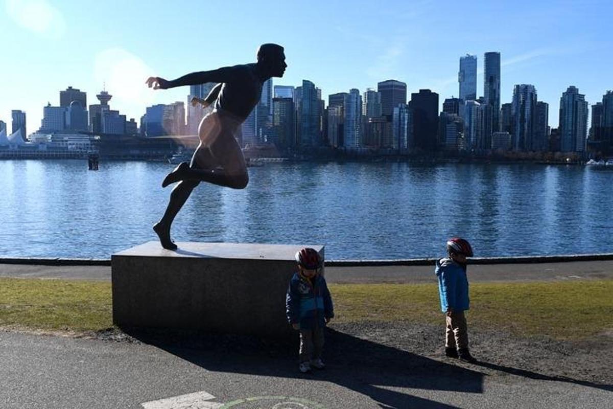 two children standing next to a statue of a man