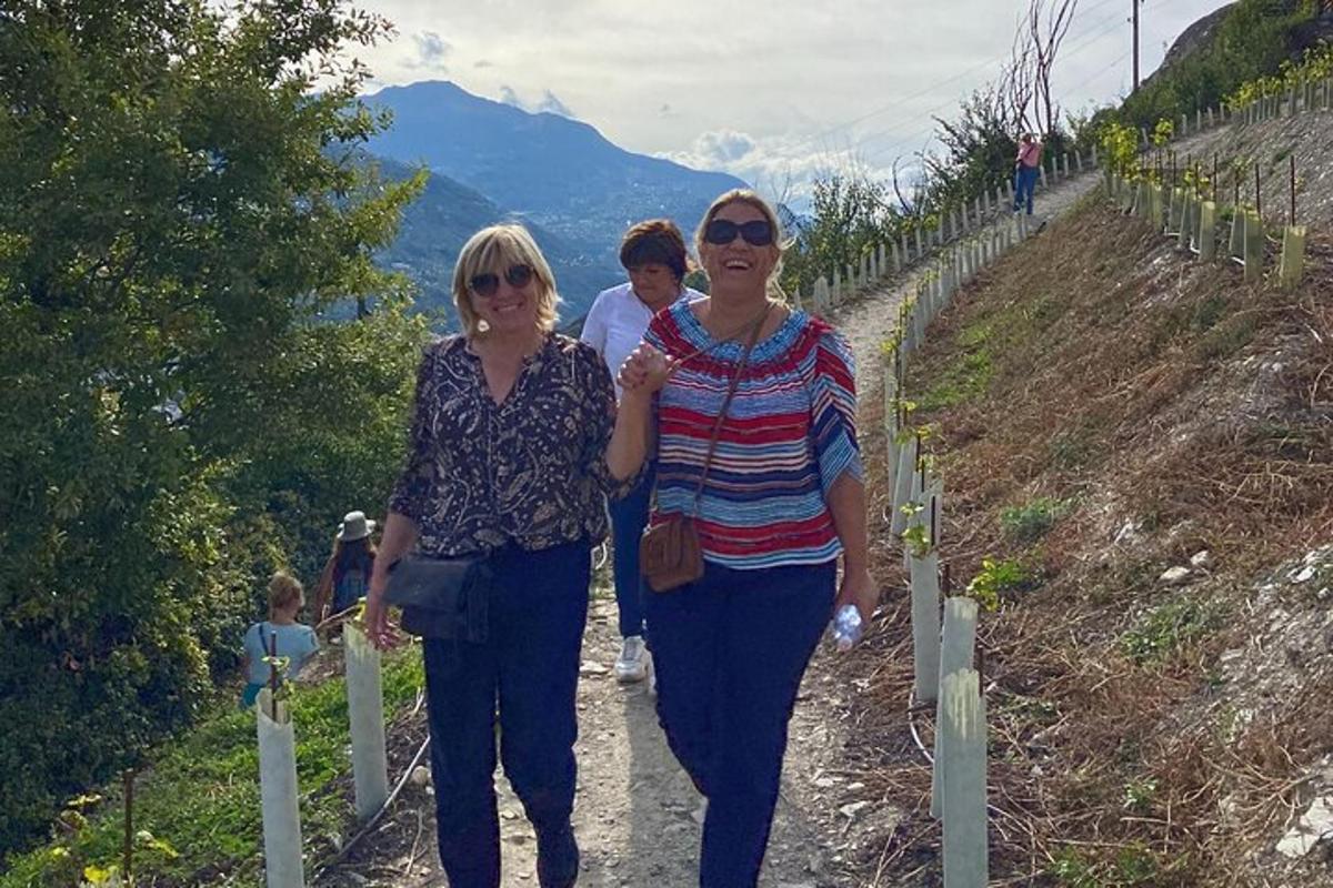 dues dones caminant per un camí en una vinya