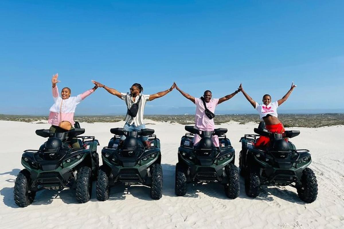 quatro pessoas levantando as mãos enquanto andam de quadriciclo na praia