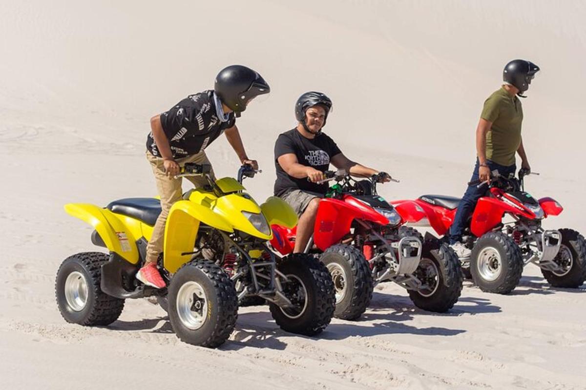 Tre mænd på ATV'er i sandet på stranden