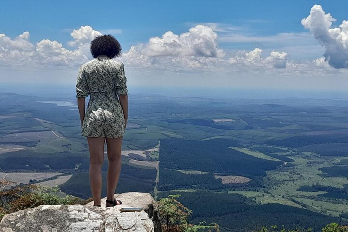Una mujer parada en la cima de una roca con vista a un valle.