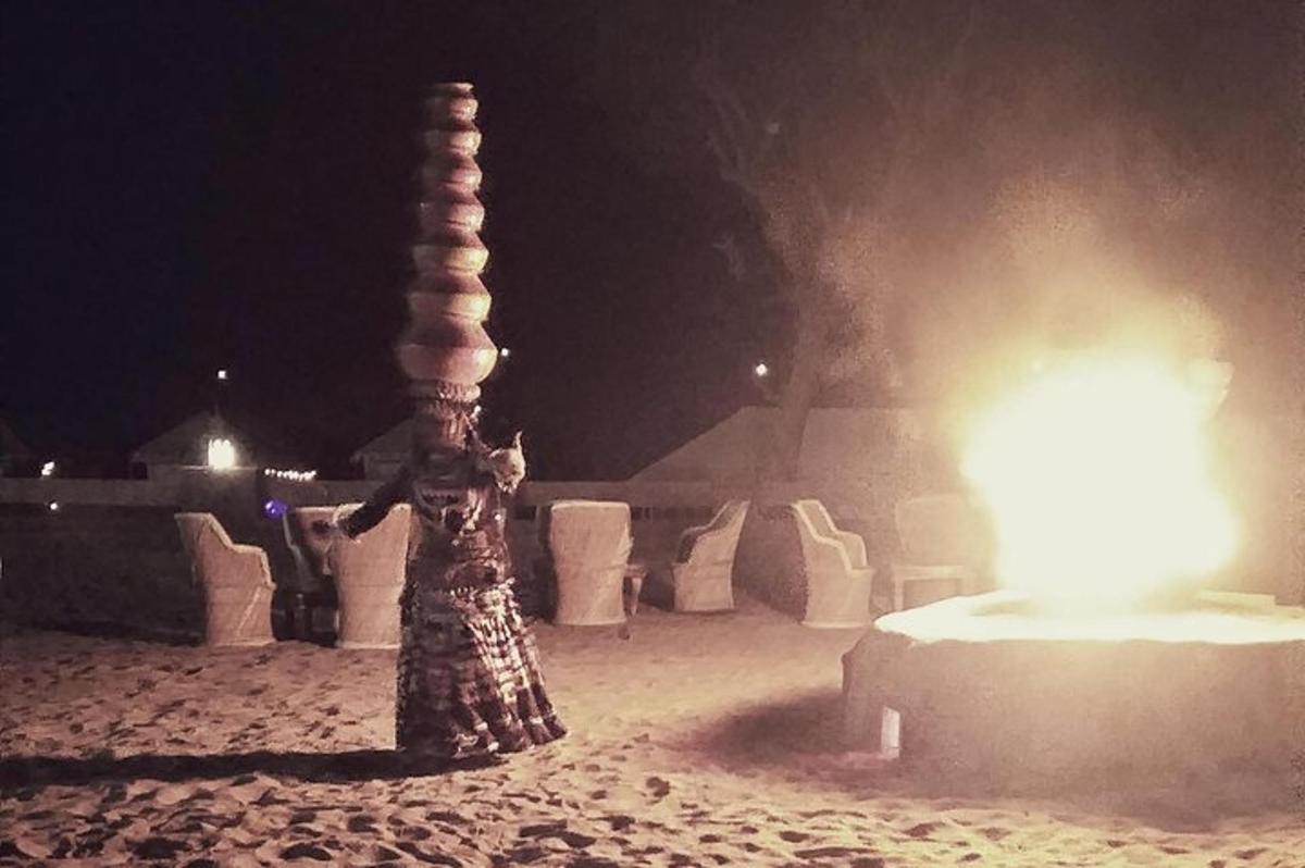 a woman standing next to a light pole in the sand