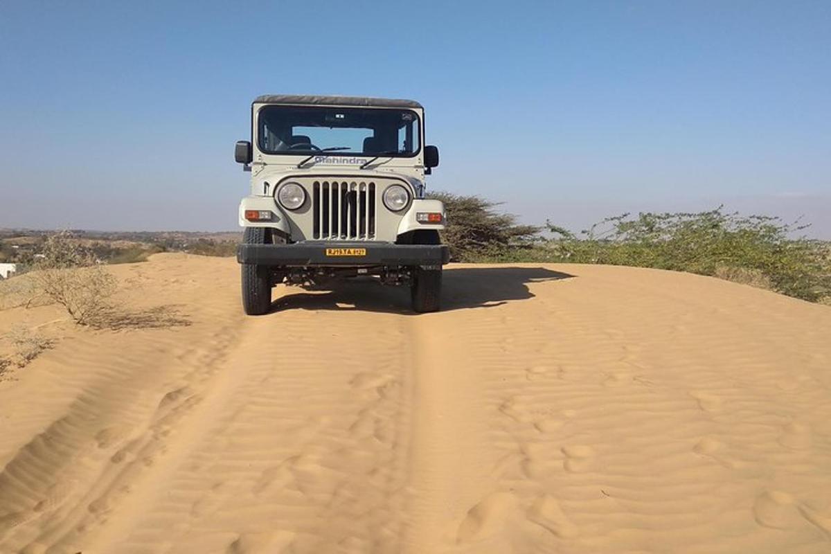 a jeep driving down a sand hill in the desert