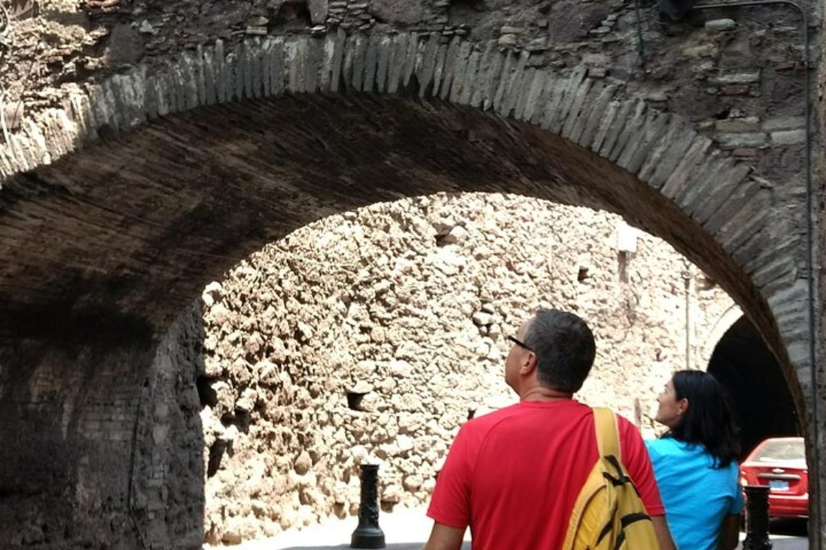 a man and a woman walking under a stone tunnel