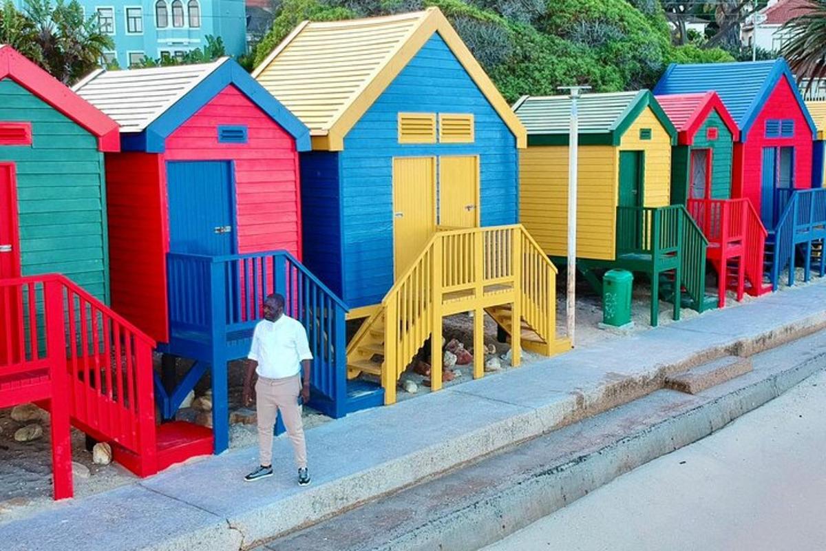 mężczyzna stojący przed rzędem kolorowych domków plażowych