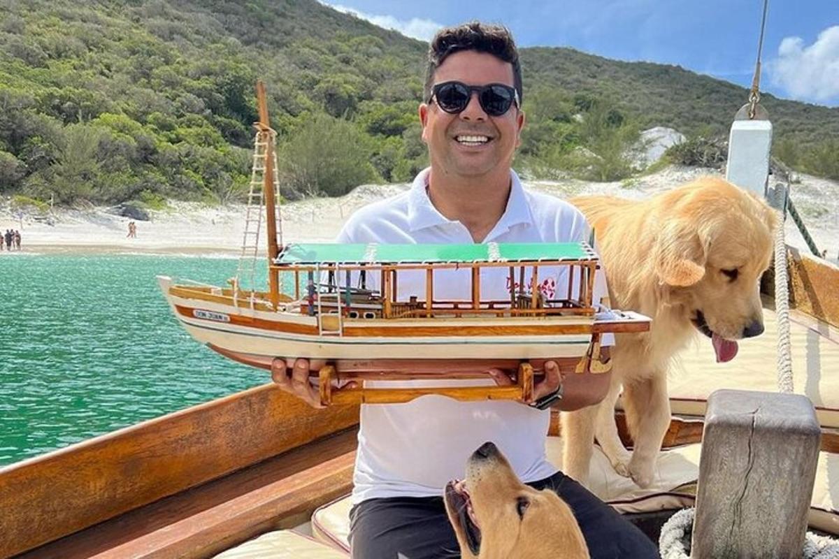 a man with a dog holding a model boat