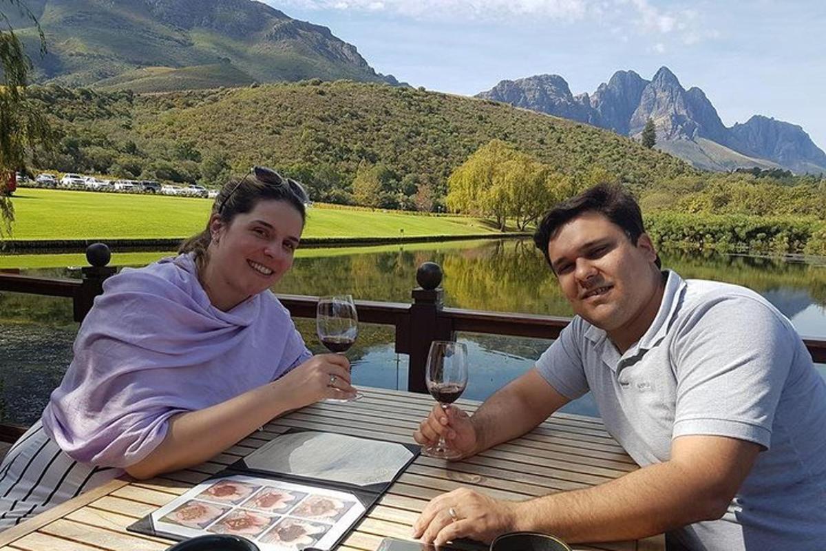 un bărbat și o femeie așezați la o masă cu pahare de vin