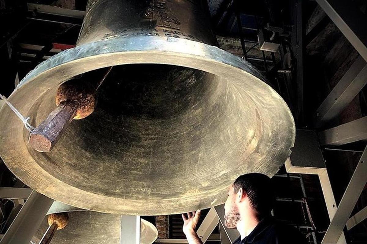 a man standing in front of a large metal bell
