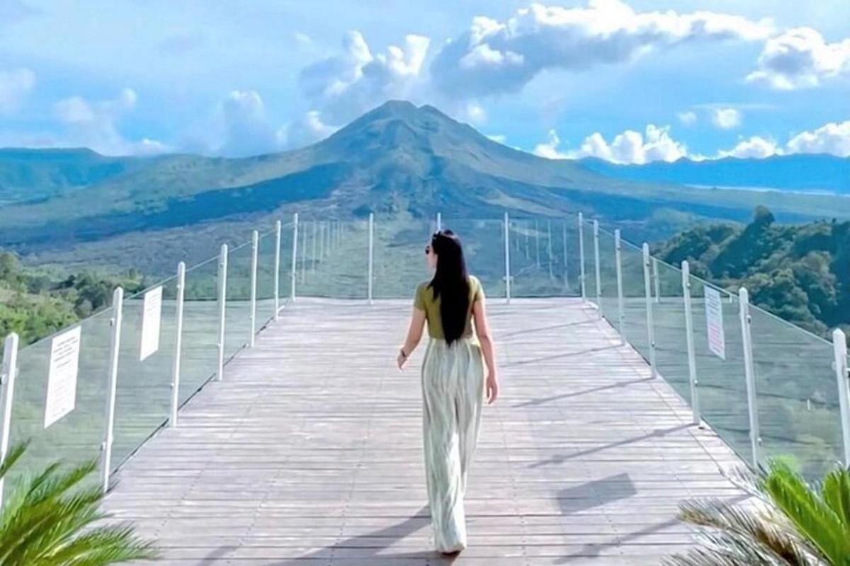 uma mulher caminhando em uma ponte com uma montanha ao fundo