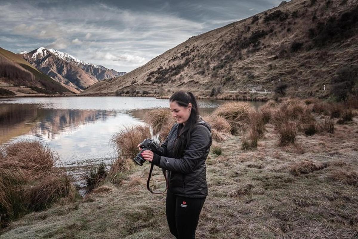 a woman taking a picture of a lake with a camera