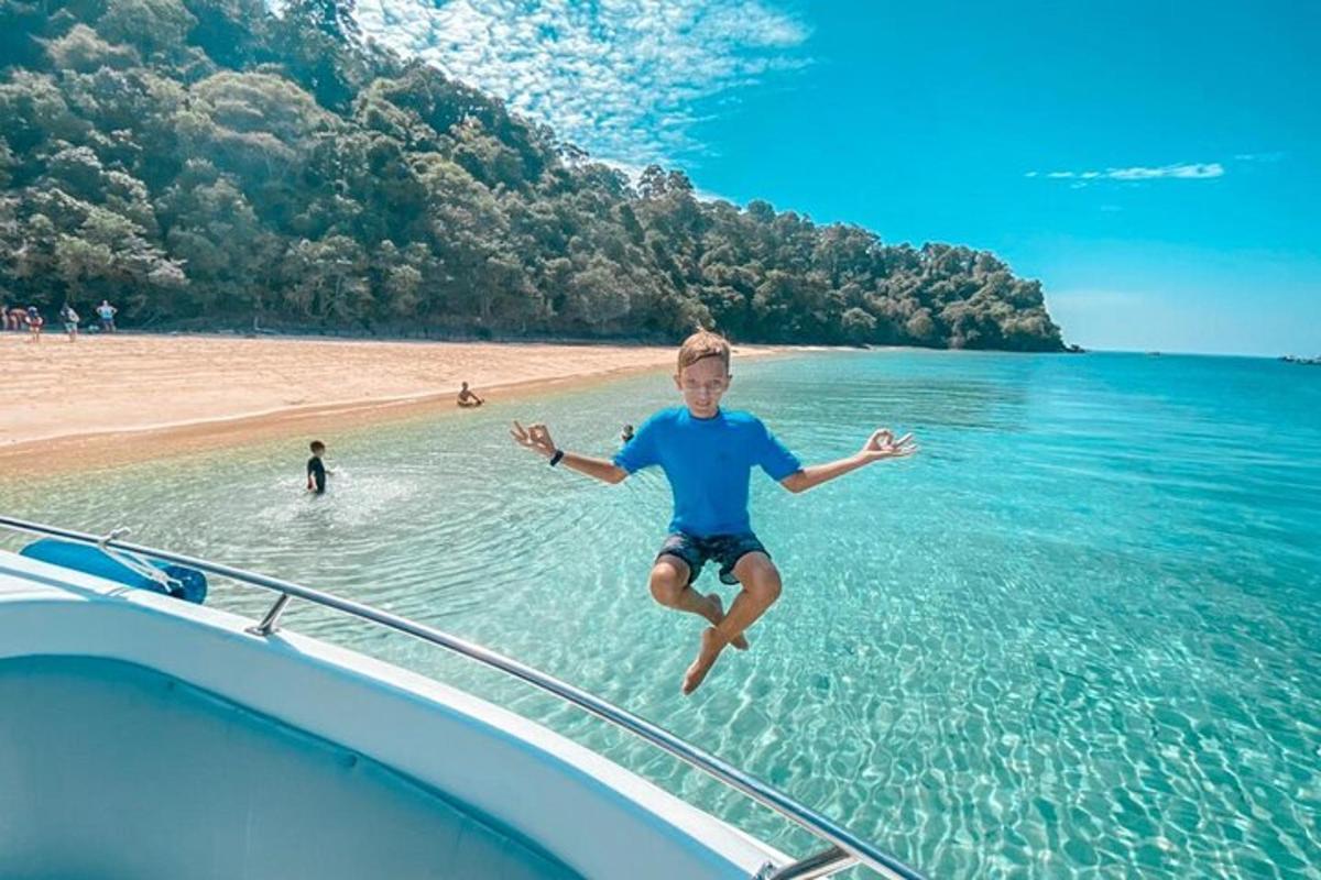 a young boy jumping off the side of a boat in the water