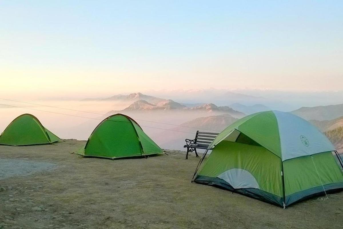 three tents on top of a mountain with a bench