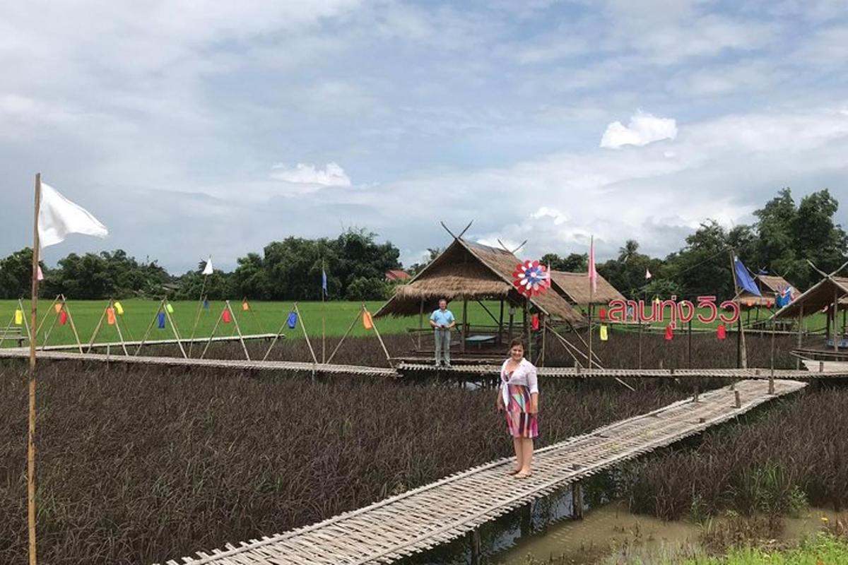 seorang wanita berdiri di jembatan dengan layang-layang di ladang